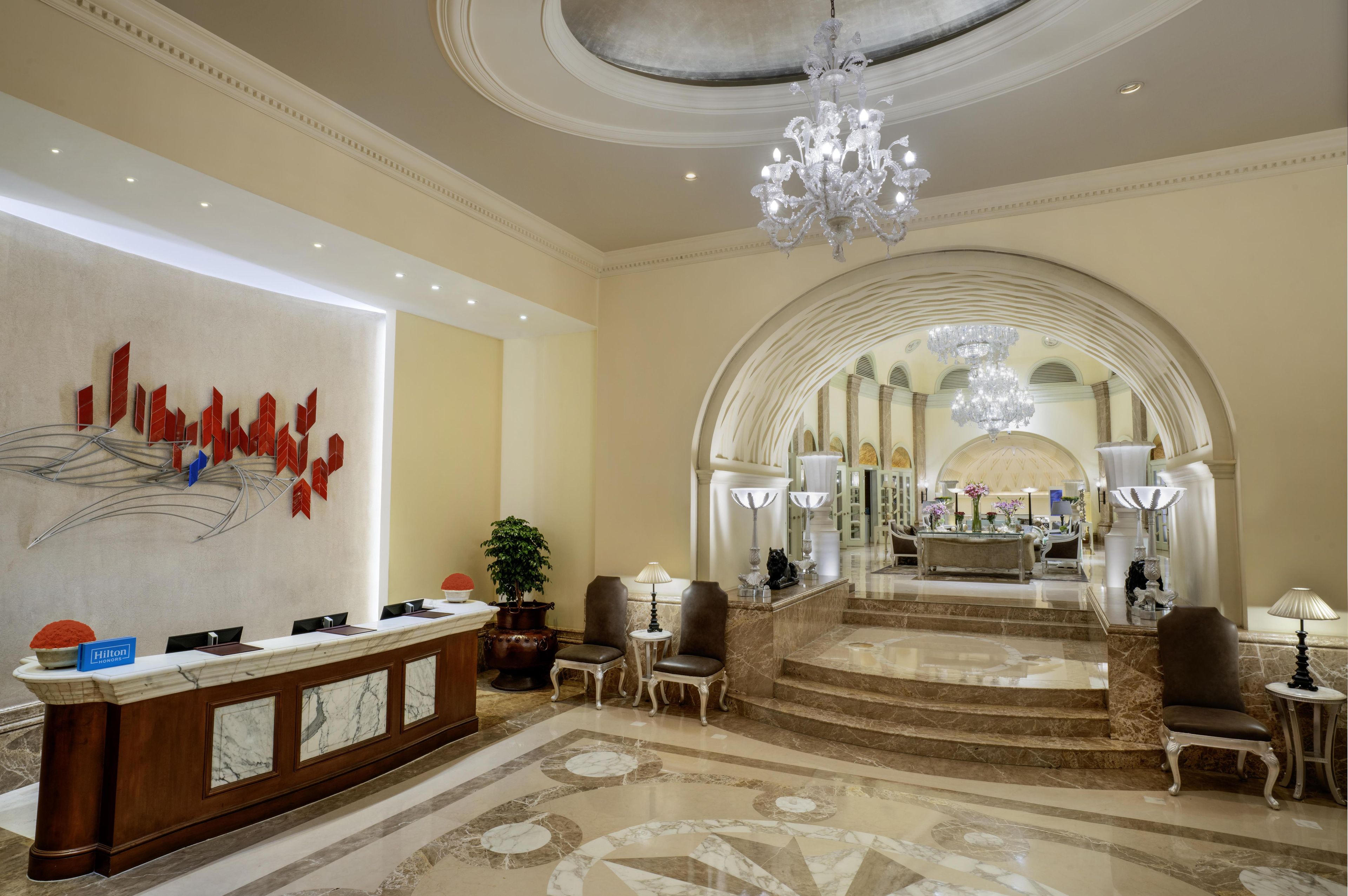 A hotel lobby with a reception desk, seating area, and a view of the interior.