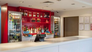 A bar area with shelves stocked with various bottles, a cash register, and a security camera on the ceiling. - Travelodge Bracknell Central (Bracknell)