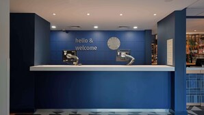 A reception desk with a 'hello & welcome' sign, a clock, and a modern design. - Travelodge Bracknell Central (Bracknell)