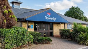 A Travelodge building with a blue awning, brick facade, and a small tower-like structure on the roof. - Travelodge Colchester Feering (Colchester)