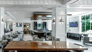 A spacious hotel lobby with a central bar area, seating arrangements, and large windows providing natural light. - Hilton Columbus at Easton (Columbus)