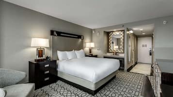 A hotel room with a large bed, bedside tables with lamps, a mirror, and a patterned floor.