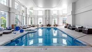 An indoor swimming pool with lounge areas and large windows. - Hilton Columbus at Easton (Columbus)