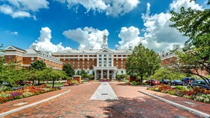 A large, red-brick building with a central entrance, surrounded by a brick pathway and flower beds. - Hilton Columbus at Easton (Columbus)