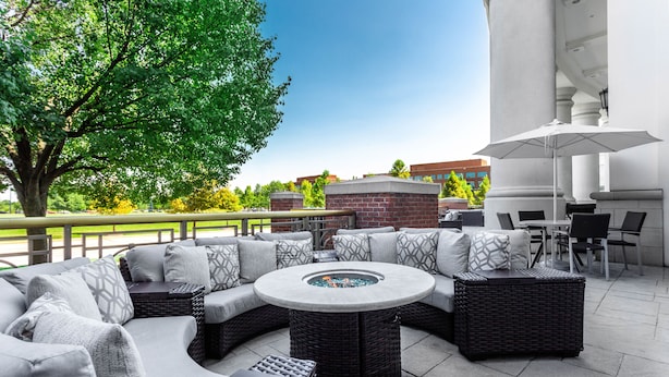 An outdoor patio with a round table, wicker furniture, and a fire pit. - Hilton Columbus at Easton (Columbus)