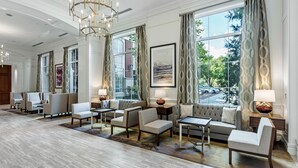 A spacious lobby with a chandelier, seating area, large windows, and artwork. - Hilton Columbus at Easton (Columbus)