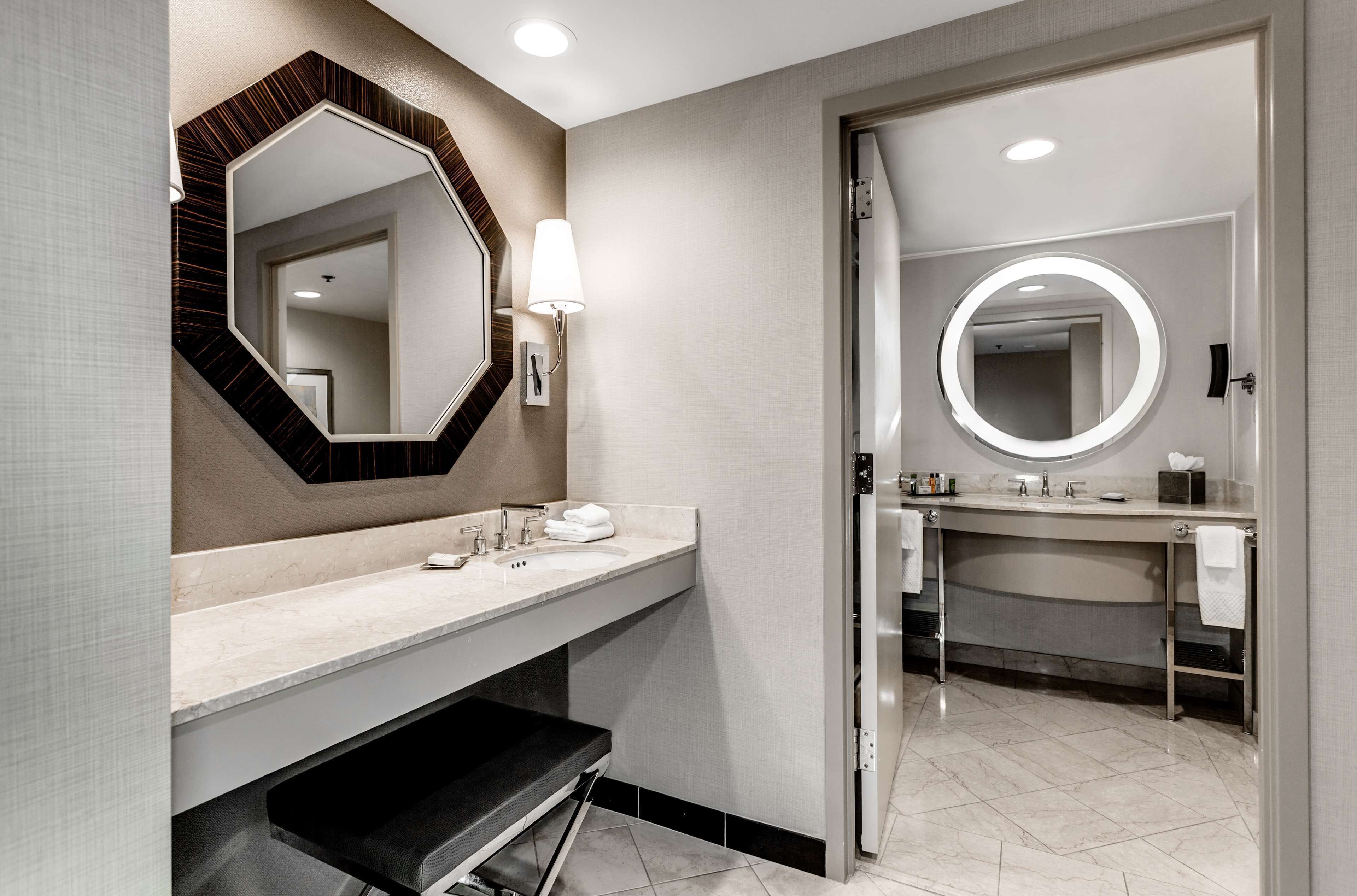 Un baño moderno con un espejo grande, un tocador con lavamanos y una zona de ducha separada.