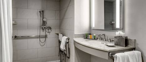 Un baño moderno con ducha, tocador con espejo y retrete.