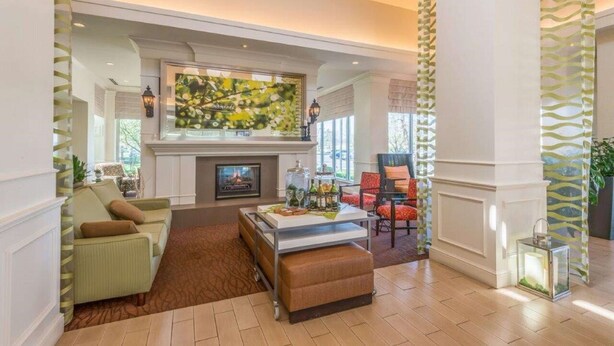 A spacious living room with a fireplace, a large abstract painting, and a cozy seating area. - Hilton Garden Inn Wichita (Wichita)
