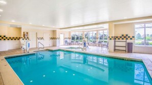 An indoor swimming pool with a tiled deck area, chairs, and a view of the outdoors. - Hilton Garden Inn Wichita (Wichita)
