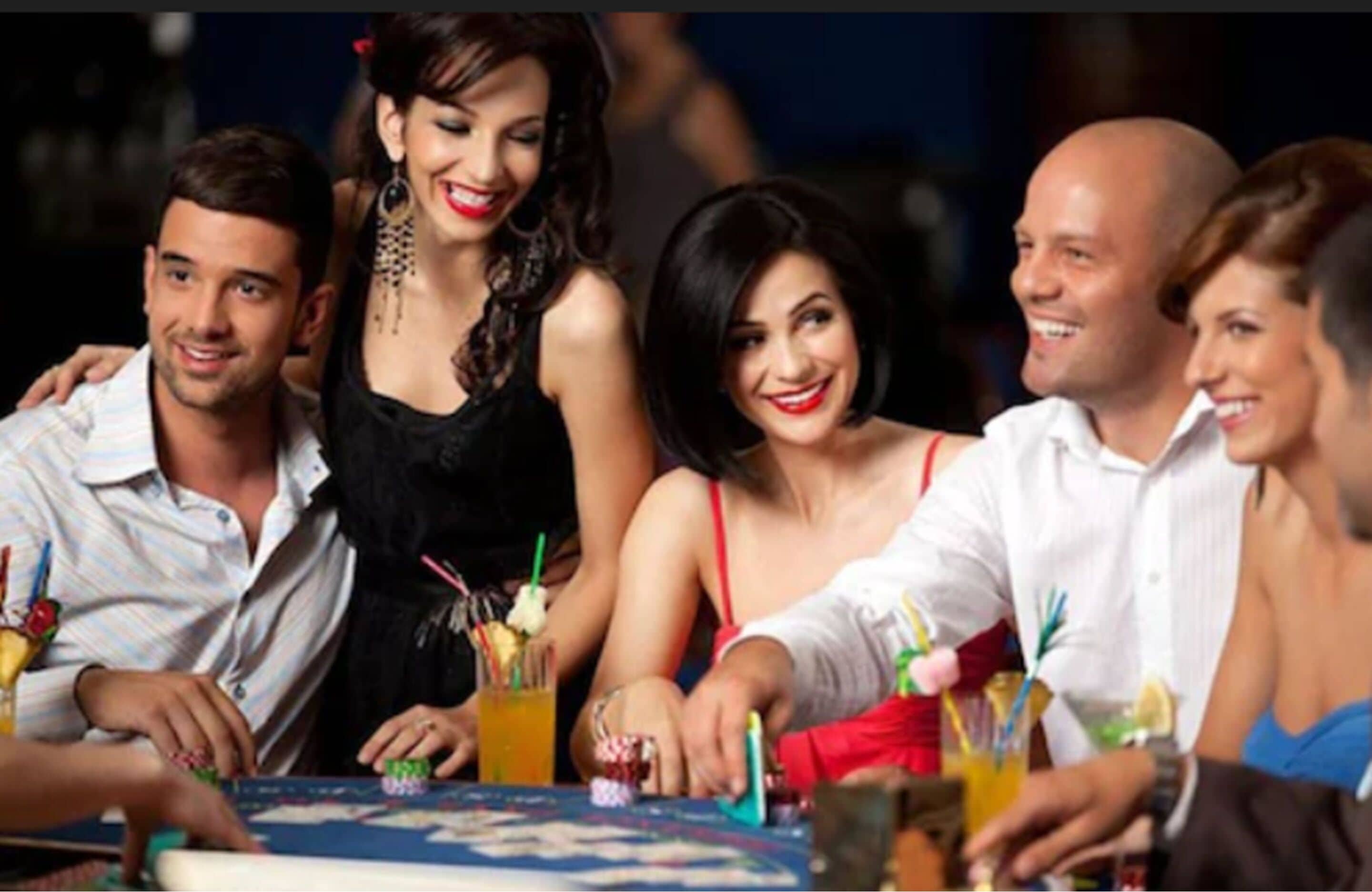 A group of people seated around a table with drinks and a board game.
