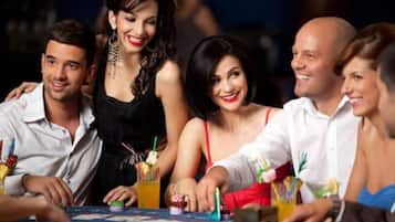 A group of people seated around a table with drinks and a board game.