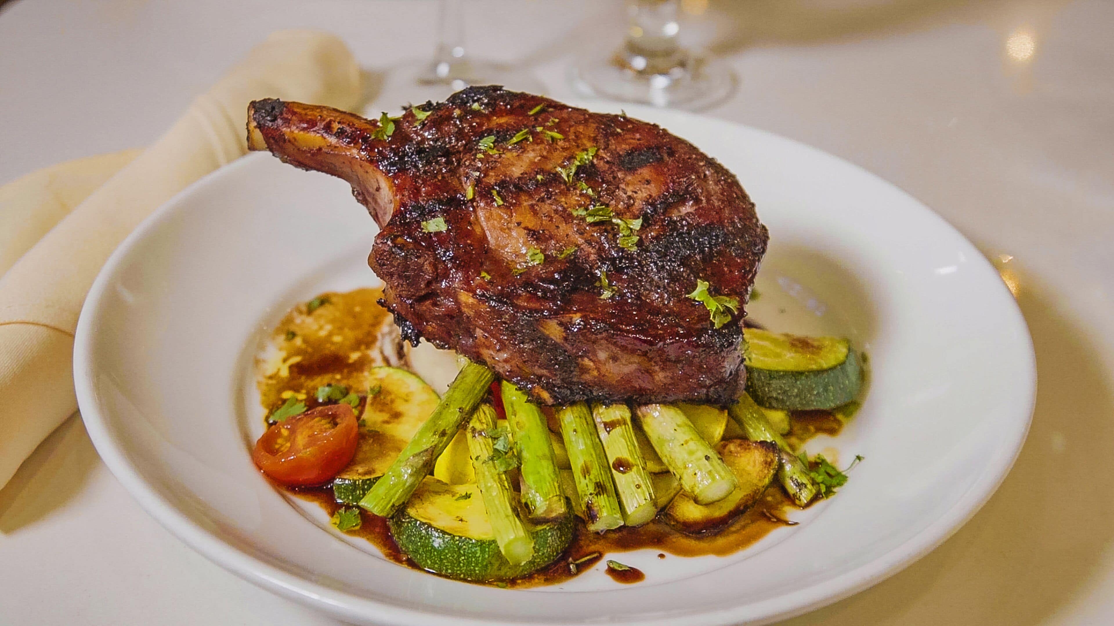 A plate with a roasted duck, zucchini, and cherry tomatoes.