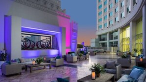 A spacious outdoor lounge area with multiple seating arrangements and a large illuminated artwork display.