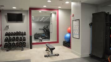 Una palestra con rastrelli per pesi, tapis roulant e palle da ginnastica.