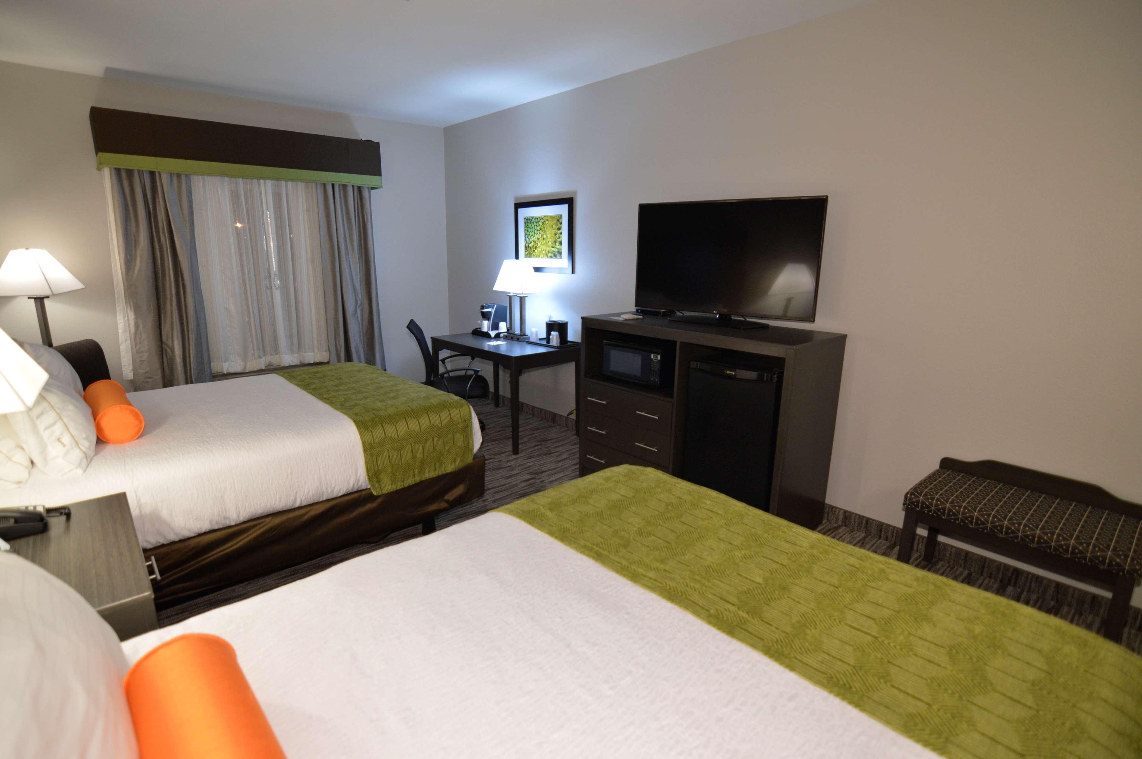Een hotelkamer met twee bedden, een bureau, een televisie en een stoel.