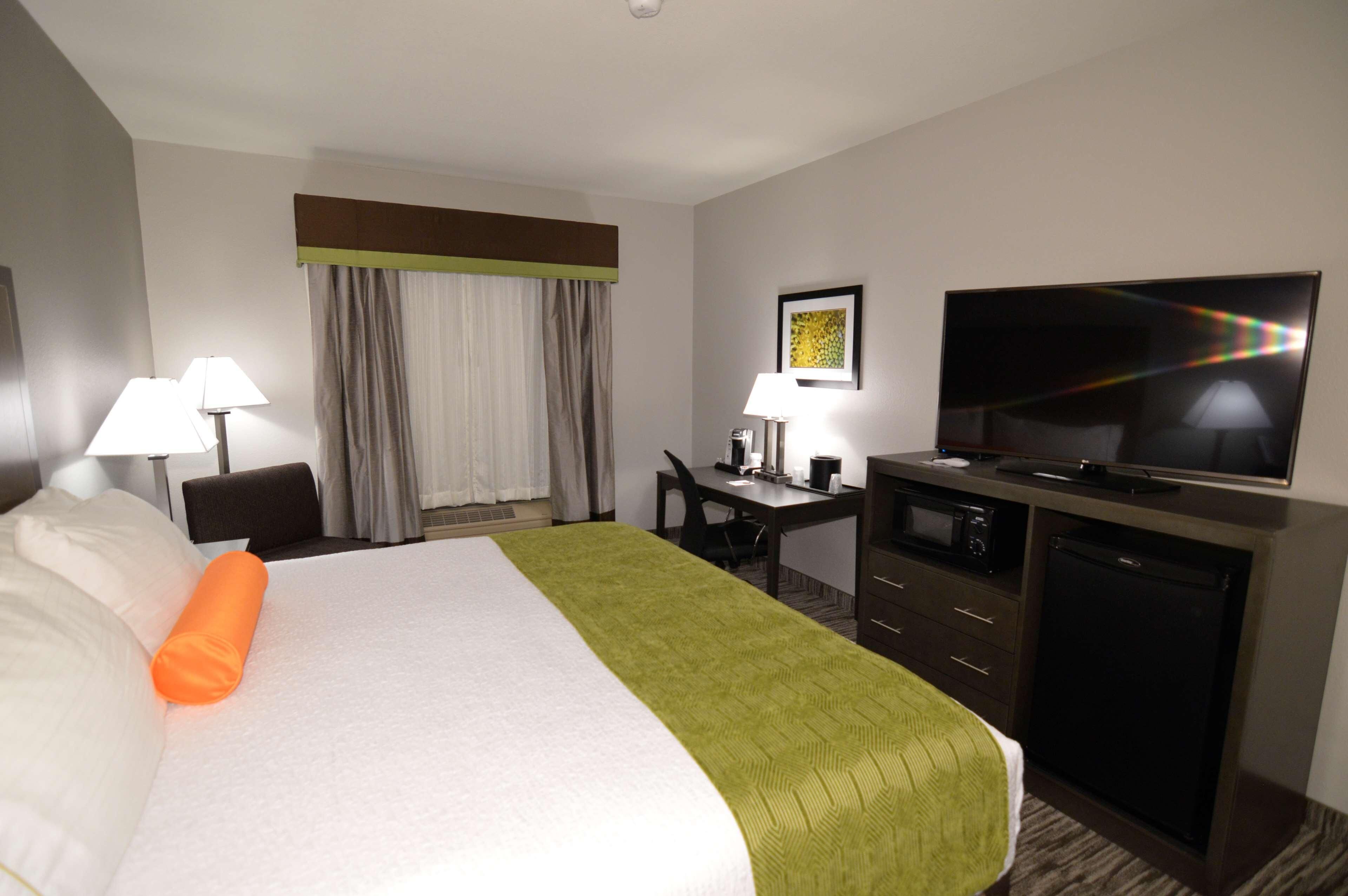 Une chambre d’hôtel équipée d’un lit, d’un bureau, d’une télévision et d’un four à micro-ondes.