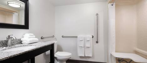 A modern bathroom with a granite sink, white toilet, and a walk-in shower with a grab bar.
