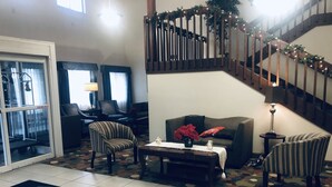 Un salón amplio con una escalera, un sofá, sillones y una mesa de centro.