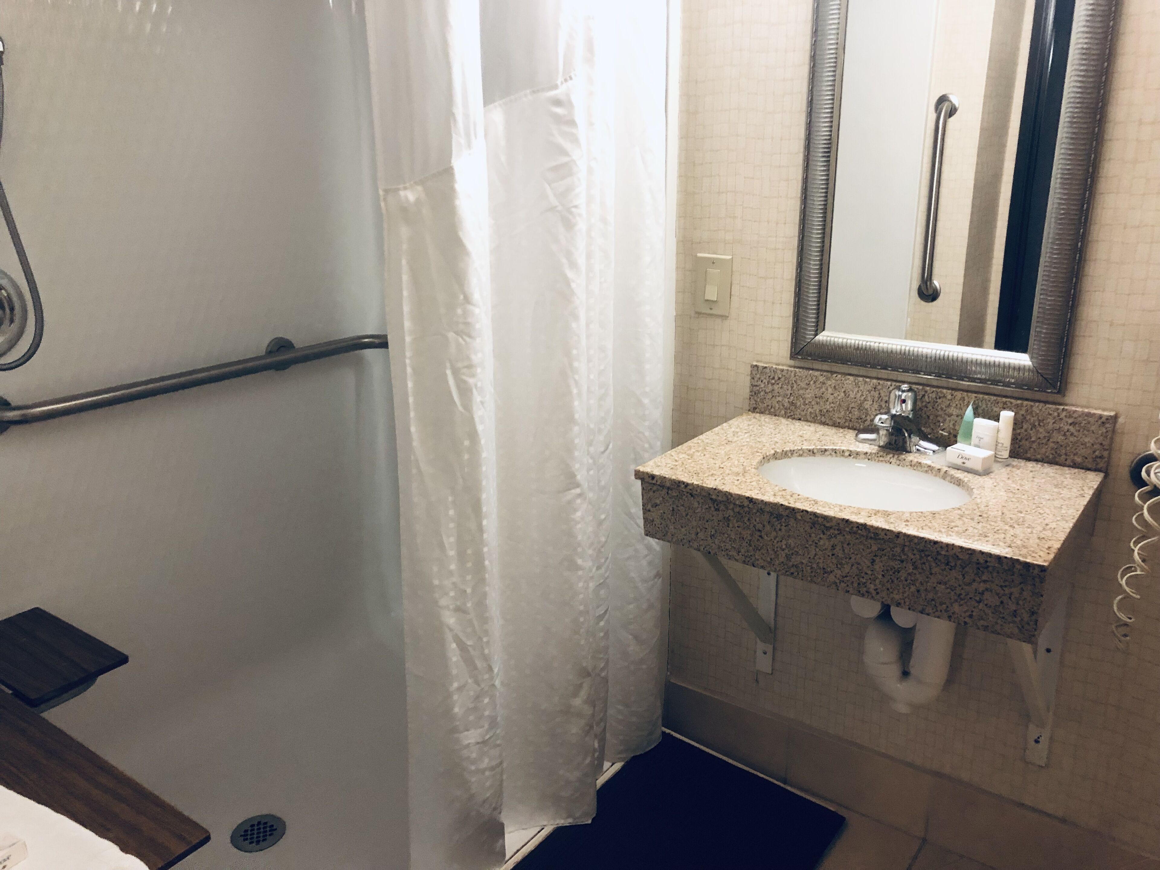 A bathroom with a shower, a sink with a mirror, and a towel rack.