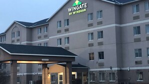 Un hotel Wingate by Wyndham con un diseño moderno, varios pisos y una zona de entrada cubierta.