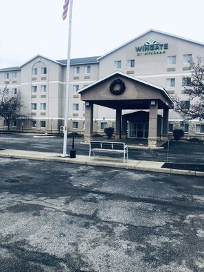 Welcome to Wingate by Wyndham, where a covered entrance invites you in, surrounded by a beautifully decorated area and a well-maintained parking lot.