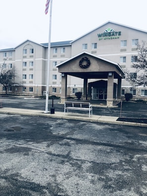 Welcome to Wingate by Wyndham, where a covered entrance invites you in, surrounded by a beautifully decorated area and a well-maintained parking lot.