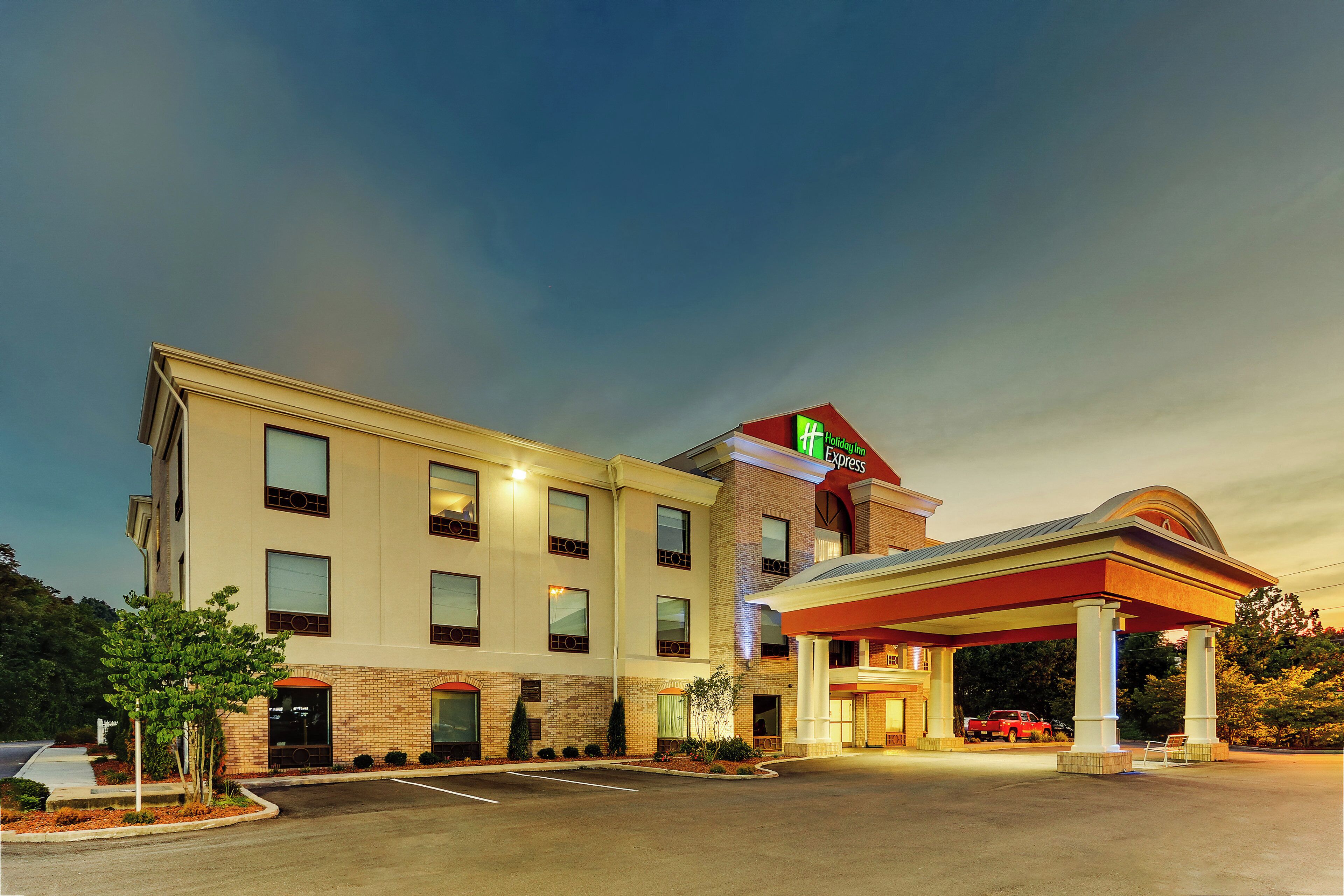 A Holiday Inn Express hotel with a gas station attached, featuring a parking lot and a red pickup truck.