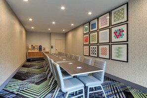 A conference room with a long table, chairs, a carpeted floor, and a wall with framed geometric patterns. - Holiday Inn Express & Suites Corbin by IHG (Corbin)