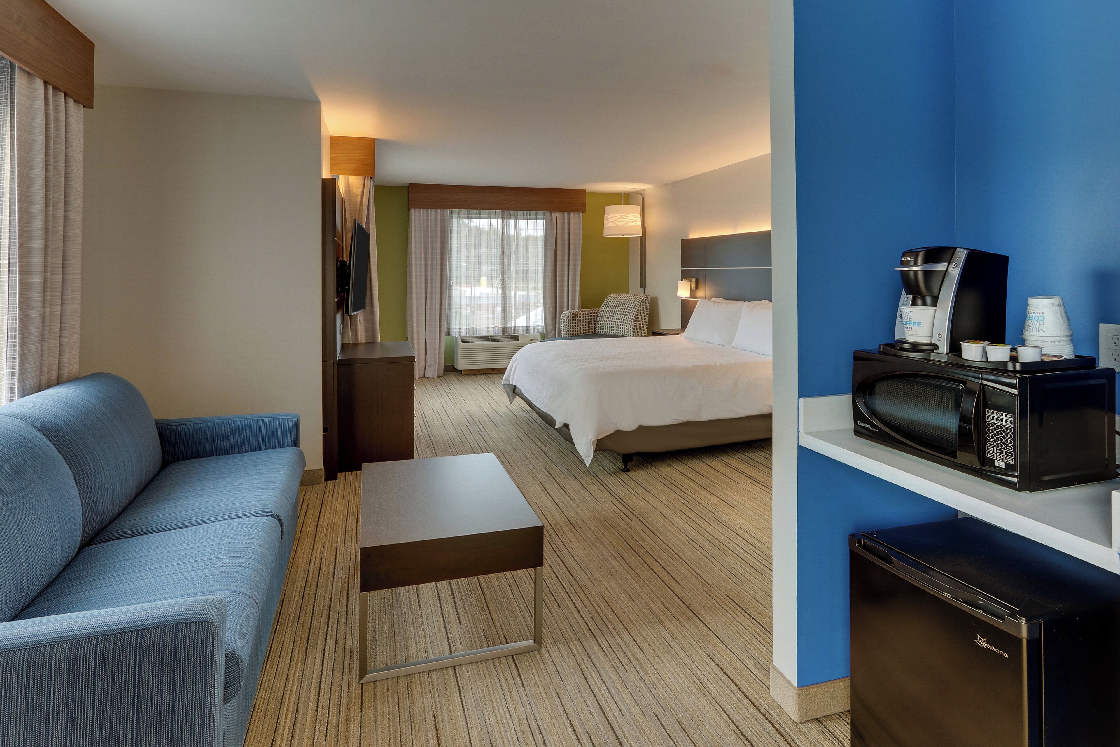 A hotel room with a bed, a sofa, a coffee maker, and a microwave.