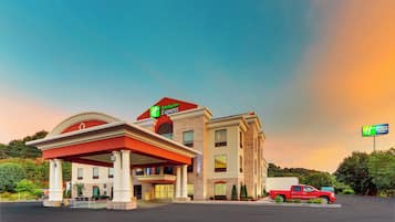 Edifício Holiday Inn Express com toldo de posto de gasolina, uma caminhonete vermelha estacionada na frente e céu azul.