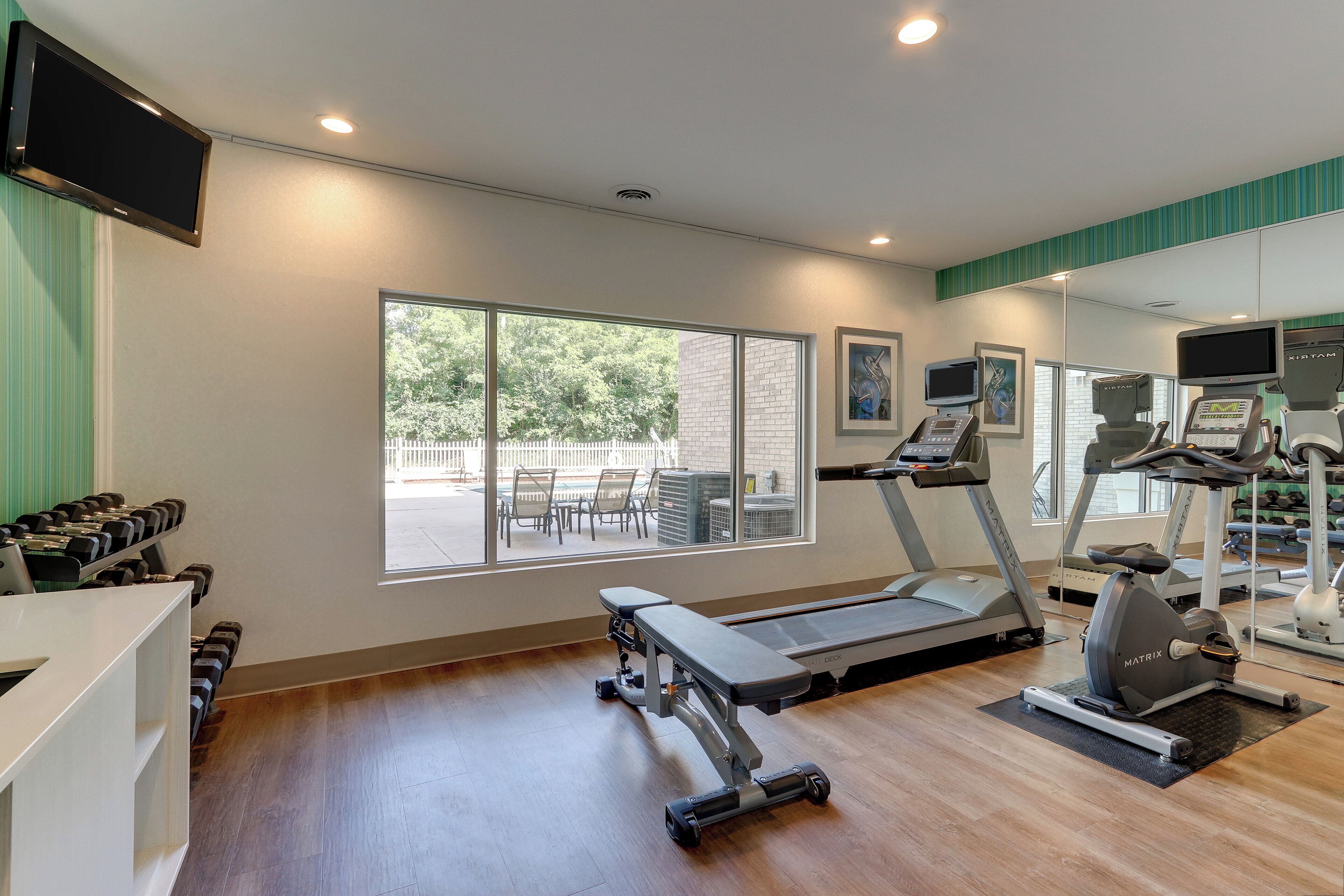 Un gimnasio con cintas de correr, mancuernas y equipamiento de ejercicio.