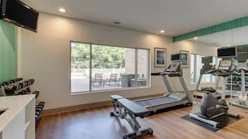 Un gimnasio con cintas de correr, mancuernas y equipamiento de ejercicio.