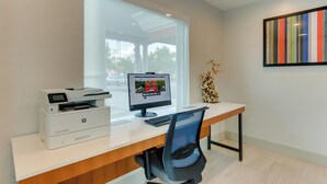 A modern office desk with a desktop computer, printer, and chair.