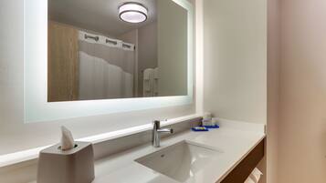 A modern bathroom with a large mirror, a white sink, and a towel rack.