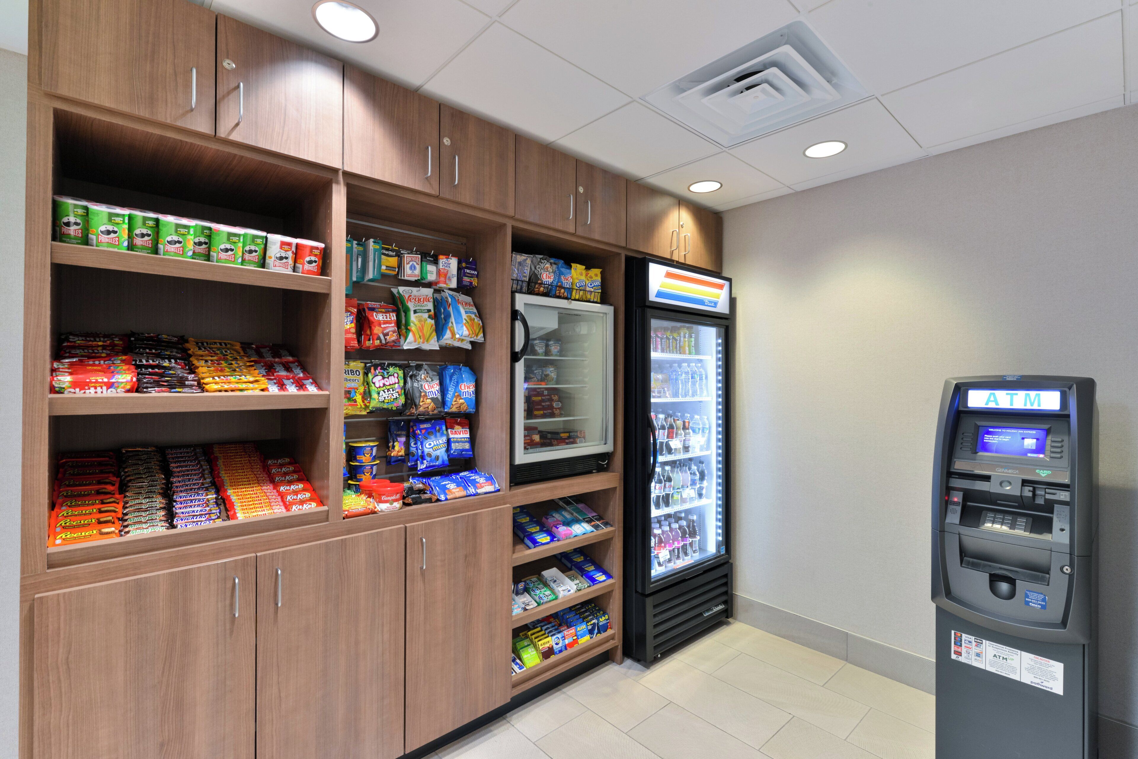 A self-service kiosk area with a refrigerated display case and a freezer, and a vending machine stocked with snacks.