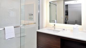 Un bagno moderno con cabina doccia in vetro, un lavandino bianco e uno specchio grande sopra il mobile.