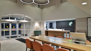 Ein moderner Konferenzraum mit einem langen Tisch, orangefarbenen Stühlen, einem Desktop-Computer und einem Empfangstresen mit einem Neon-Schild.