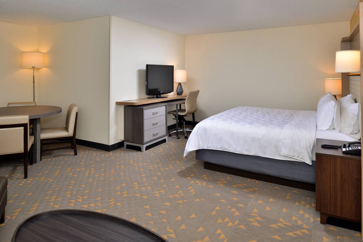Une chambre d’hôtel équipée d’un lit, d’un bureau, d’une chaise, d’une télévision et de lampes.