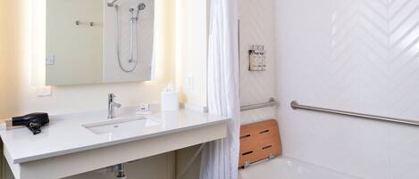 Un baño moderno con lavamanos, espejo y ducha blancos.
