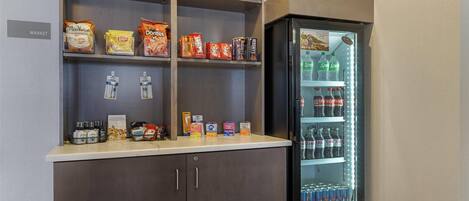 A vending machine stocked with snacks and beverages, located next to a wooden cabinet with shelves above.