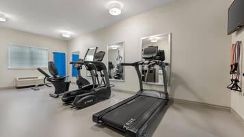 Un gimnasio con cintas de correr, una bicicleta estática y una máquina de remo.