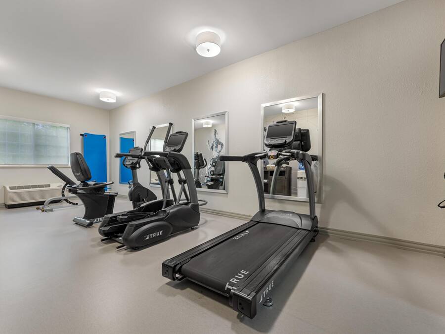Un gimnasio con cintas de correr, una bicicleta estática y una máquina de remo.