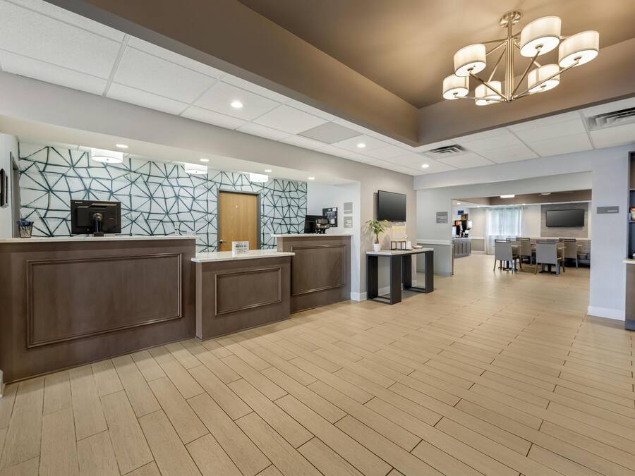 Una hall d'albergo moderna con una reception, un'area relax e un grande lampadario.