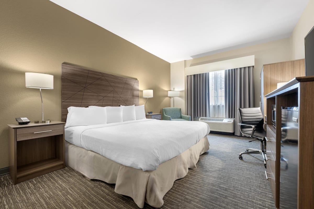 Een hotelkamer met een groot bed, nachtkastjes, een bureau, een stoel en een televisie.