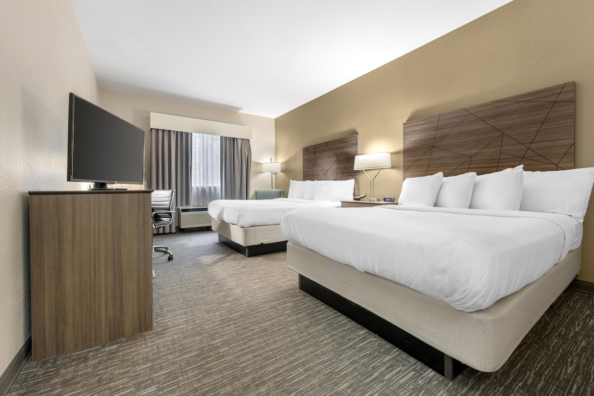 Een hotelkamer met twee bedden, een televisie, een bureau en een stoel.