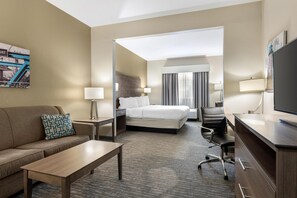 Une chambre d’hôtel comprenant un lit, un bureau, une chaise, un canapé et un téléviseur.