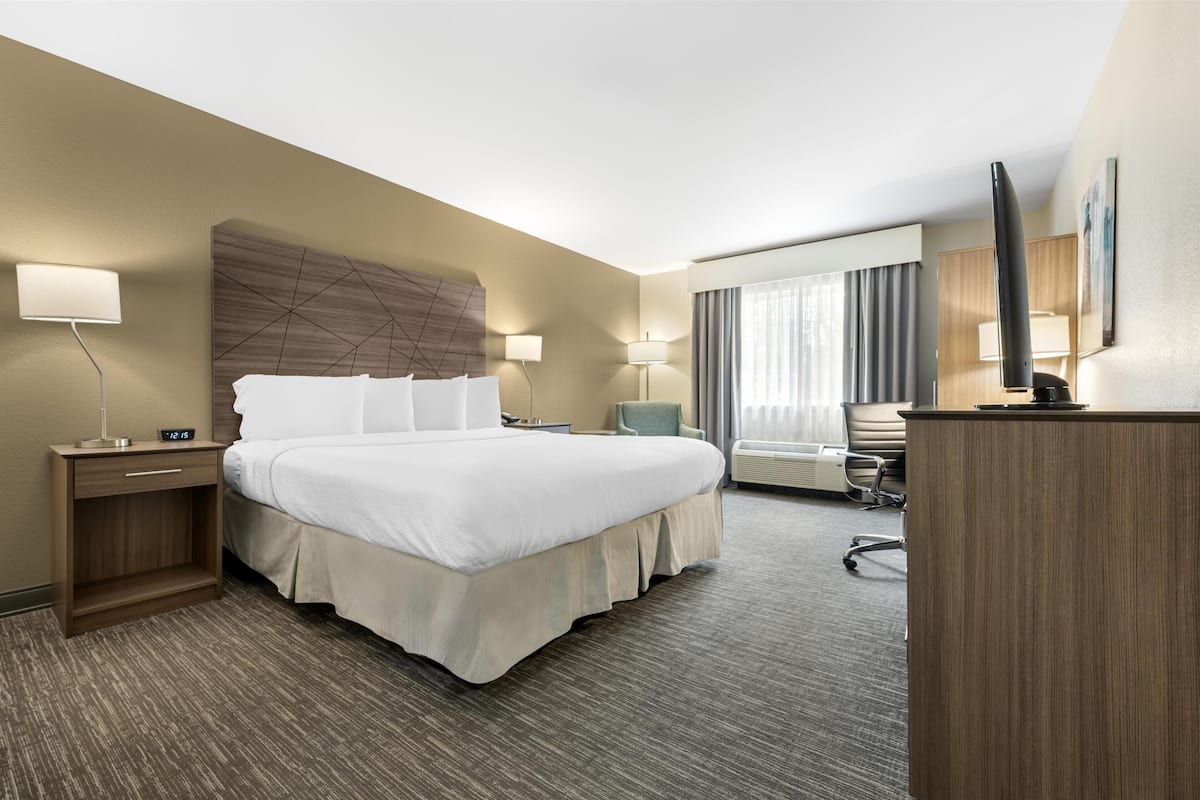 Een hotelkamer met een groot bed, nachtkastjes, een bureau en een stoel.