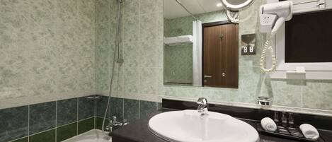 Un baño con bañera, lavamanos, secador de pelo y espejo.