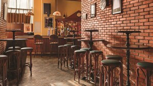 Un espace bar avec des murs en briques, des tabourets en bois et des lampes suspendues.